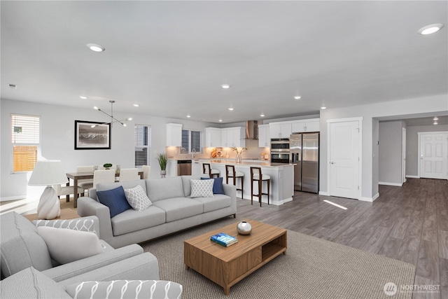 living area with dark wood-style floors, baseboards, an inviting chandelier, and recessed lighting