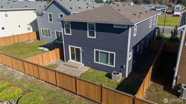 rear view of house featuring a patio, a fenced backyard, roof with shingles, a yard, and central AC