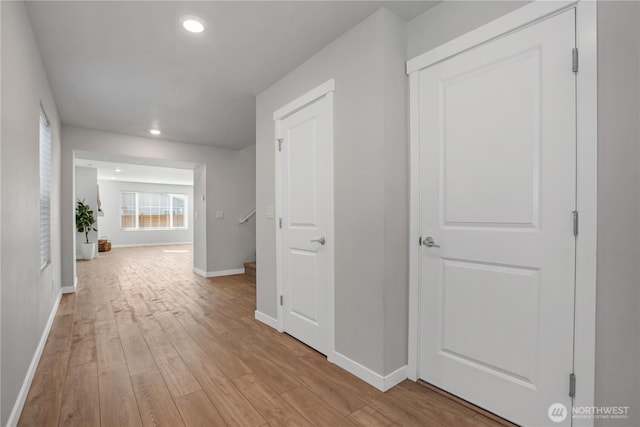 corridor with light wood-type flooring, baseboards, and recessed lighting