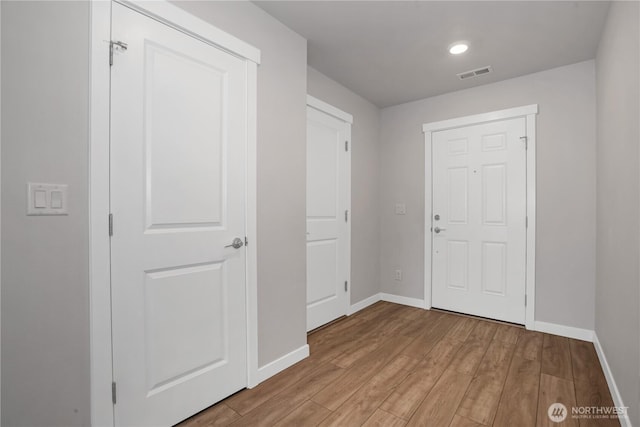 foyer entrance featuring wood finished floors, visible vents, and baseboards