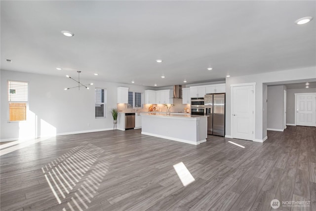 unfurnished living room with dark wood-type flooring, recessed lighting, a notable chandelier, and baseboards