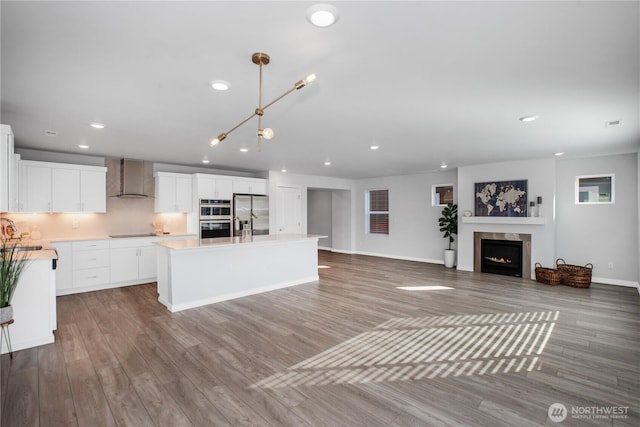 kitchen with appliances with stainless steel finishes, a sink, wall chimney exhaust hood, and wood finished floors