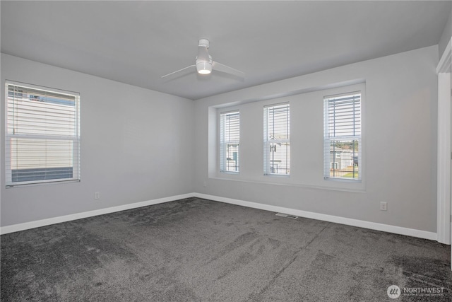 carpeted spare room with plenty of natural light, a ceiling fan, and baseboards