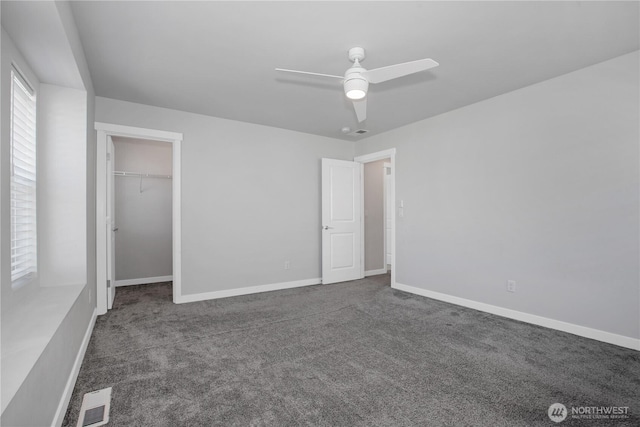 unfurnished bedroom featuring visible vents, dark carpet, and baseboards