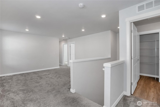 hallway featuring recessed lighting, baseboards, visible vents, and an upstairs landing