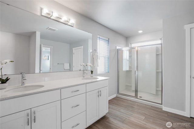 full bathroom with visible vents, a sink, a shower stall, and wood finished floors