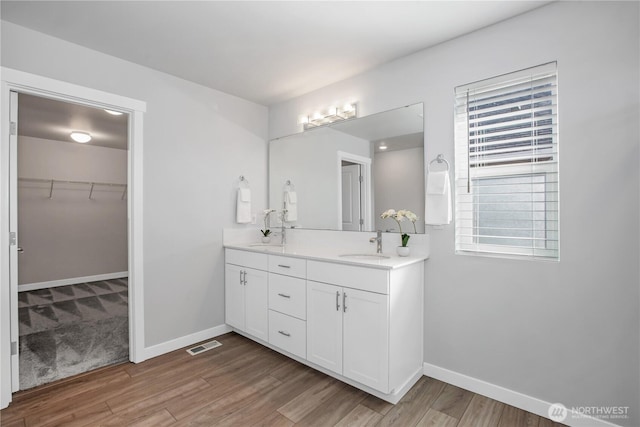 full bath with wood finished floors, a sink, visible vents, and baseboards