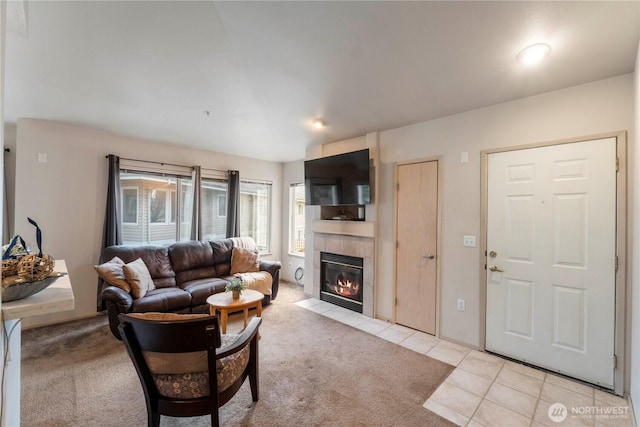 living area featuring light tile patterned floors, light carpet, and a tiled fireplace