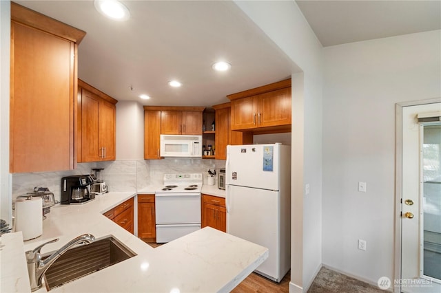 kitchen with a sink, backsplash, recessed lighting, white appliances, and light countertops