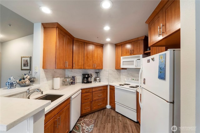 kitchen featuring white appliances, backsplash, wood finished floors, and light countertops