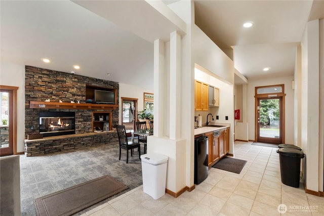 interior space featuring a sink, a stone fireplace, light tile patterned flooring, indoor wet bar, and dishwasher