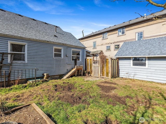 back of house featuring roof with shingles and fence