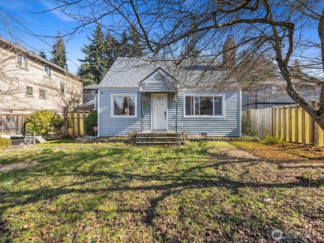 view of front facade with a shingled roof, a front yard, fence, and a chimney