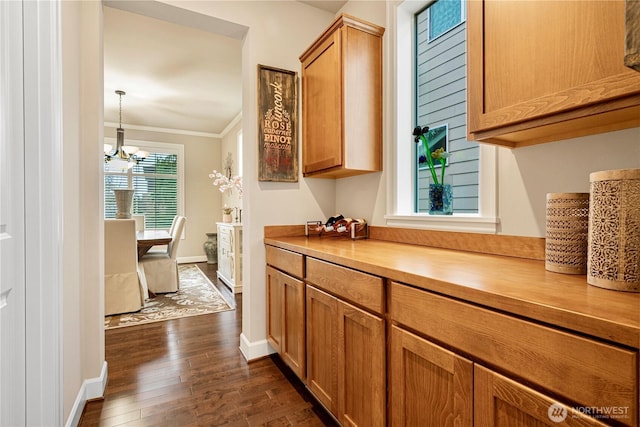 hallway with a chandelier, dark wood-type flooring, baseboards, and ornamental molding