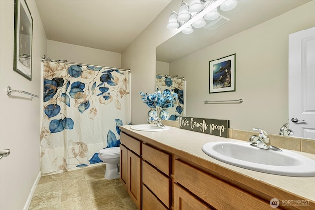 bathroom featuring a sink, baseboards, toilet, and double vanity