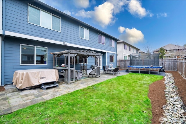 rear view of house featuring a trampoline, a lawn, a fenced backyard, a pergola, and a patio