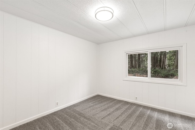 carpeted spare room with baseboards and a textured ceiling