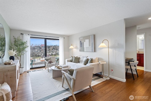 living room featuring a textured ceiling, hardwood / wood-style flooring, and baseboards