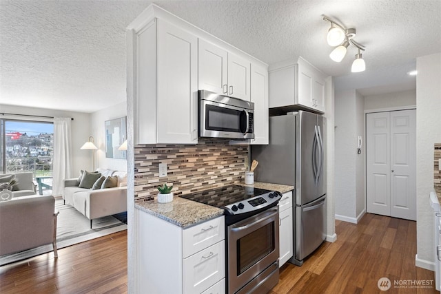 kitchen featuring stainless steel appliances, dark wood-style flooring, white cabinetry, open floor plan, and decorative backsplash