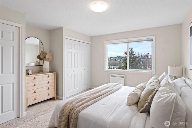 bedroom with light carpet, a textured ceiling, baseboards, and a closet