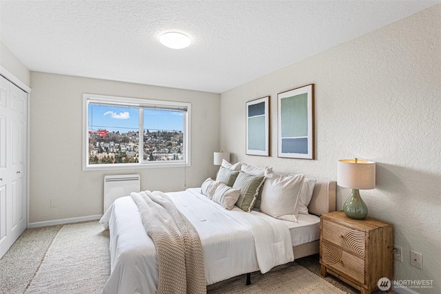 carpeted bedroom featuring a textured wall, a textured ceiling, and baseboards