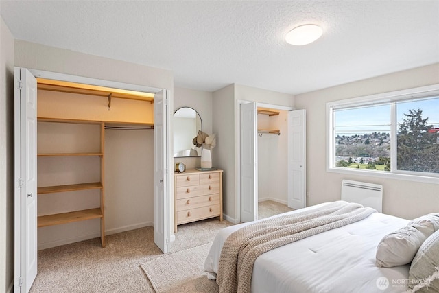 bedroom featuring light carpet, a textured ceiling, and baseboards