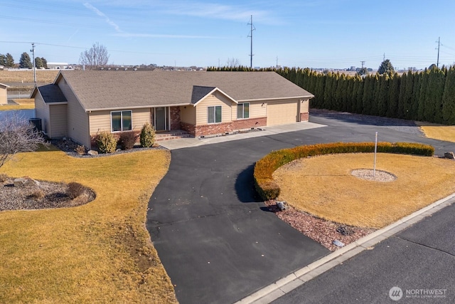 ranch-style home featuring aphalt driveway, a garage, brick siding, and a front lawn