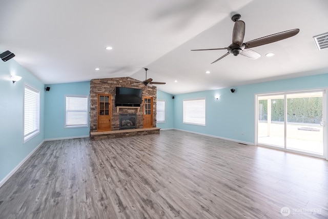 unfurnished living room featuring ceiling fan, a fireplace, vaulted ceiling, and wood finished floors