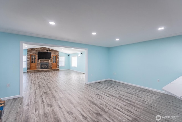 unfurnished living room with lofted ceiling, recessed lighting, a fireplace, wood finished floors, and baseboards