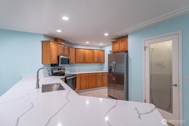 kitchen featuring light stone countertops, stainless steel appliances, a sink, and recessed lighting