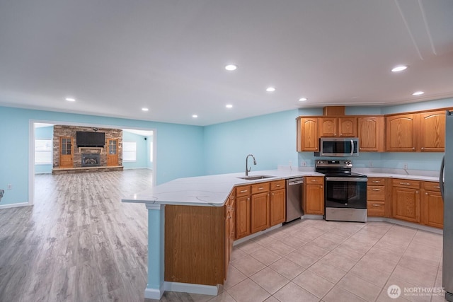 kitchen featuring recessed lighting, a peninsula, a sink, open floor plan, and appliances with stainless steel finishes