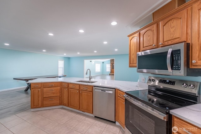 kitchen with stainless steel appliances, recessed lighting, a sink, light stone countertops, and a peninsula