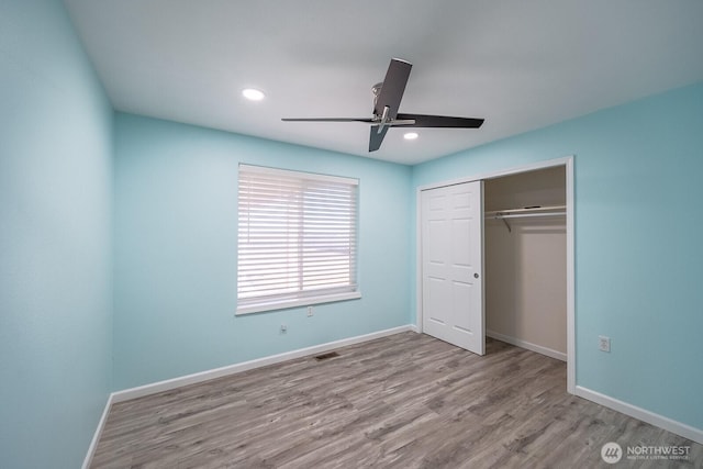 unfurnished bedroom featuring a closet, visible vents, baseboards, and wood finished floors