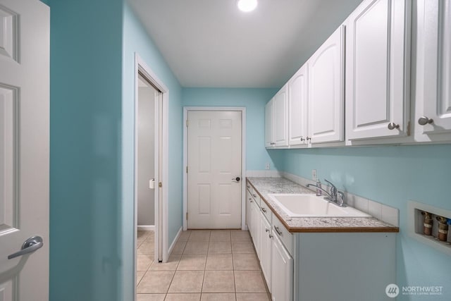 clothes washing area featuring washer hookup, light tile patterned flooring, a sink, and cabinet space