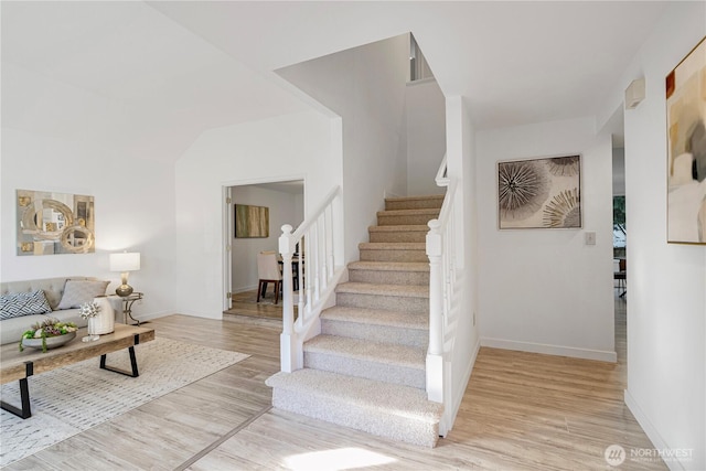 staircase featuring wood finished floors and baseboards