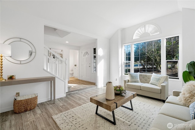 living area featuring lofted ceiling, stairs, baseboards, and wood finished floors