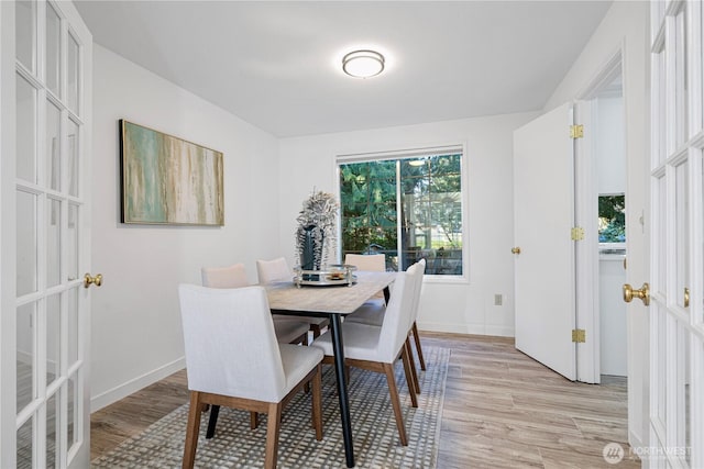 dining area featuring light wood-style floors, french doors, and baseboards