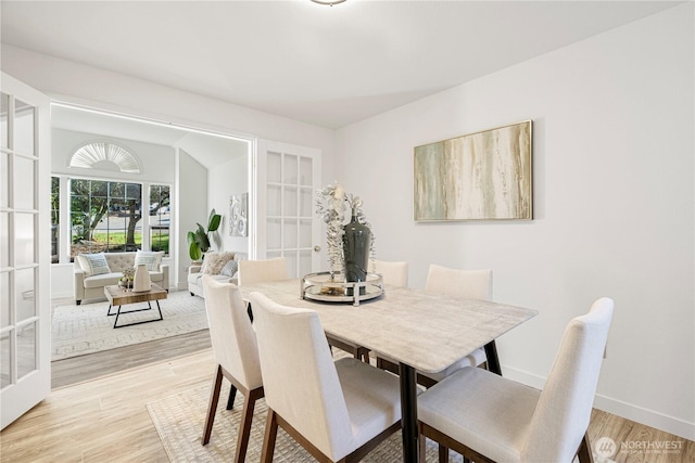 dining area featuring light wood finished floors, baseboards, and french doors