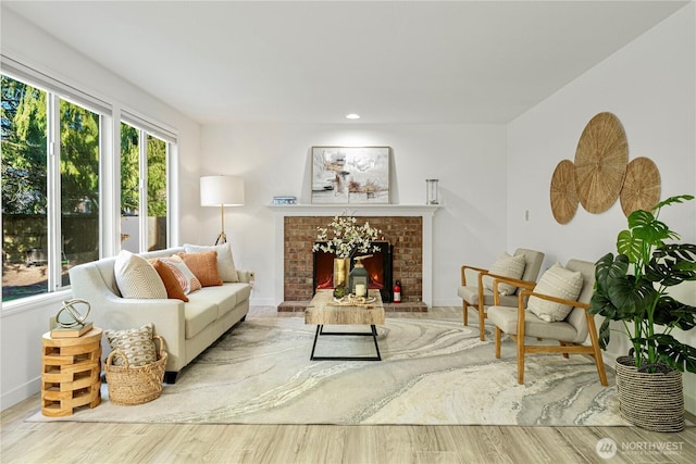 living area with recessed lighting, a brick fireplace, wood finished floors, and baseboards