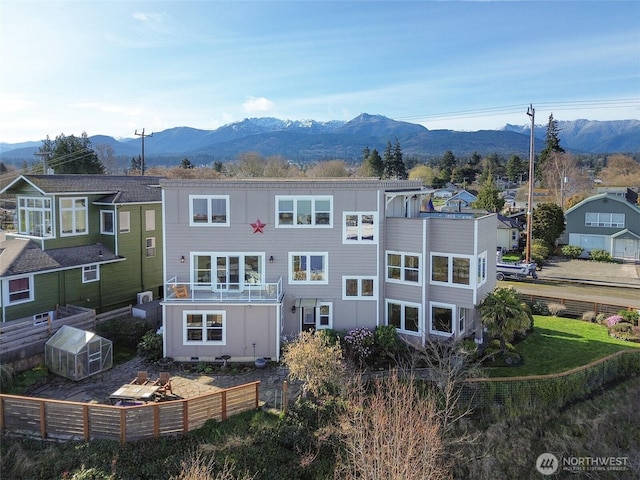 back of property featuring an outbuilding, a mountain view, and a greenhouse
