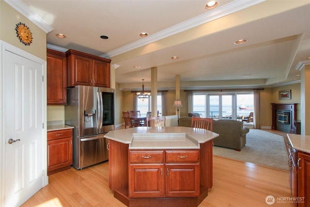 kitchen with stainless steel refrigerator with ice dispenser, open floor plan, light wood-style floors, and ornamental molding