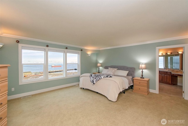 bedroom featuring baseboards, ensuite bath, light colored carpet, and ornamental molding