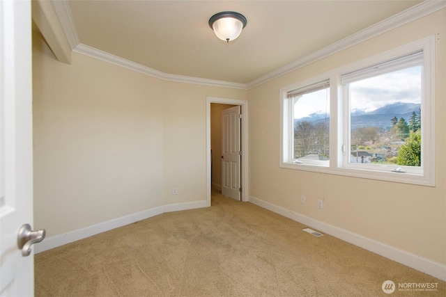 empty room with crown molding, light colored carpet, visible vents, a mountain view, and baseboards