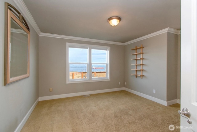 carpeted spare room with baseboards, ornamental molding, and visible vents
