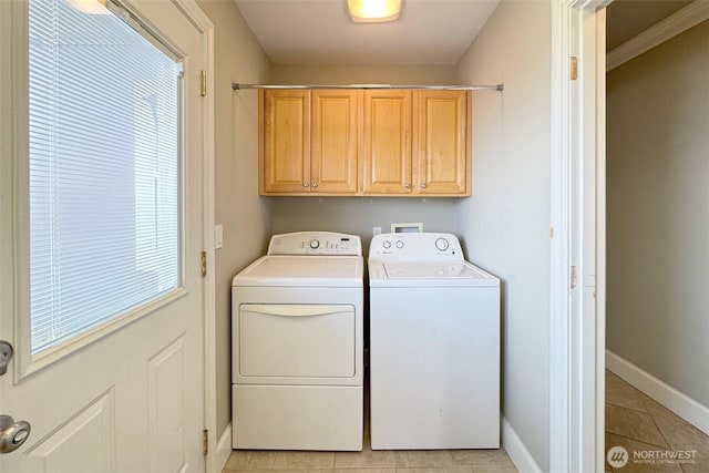 clothes washing area with light tile patterned flooring, washing machine and dryer, baseboards, and cabinet space