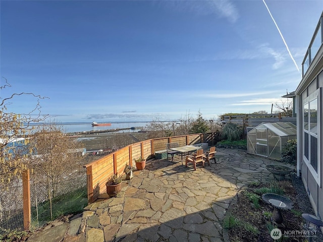 view of patio / terrace with fence, an exterior structure, an outdoor structure, and a water view