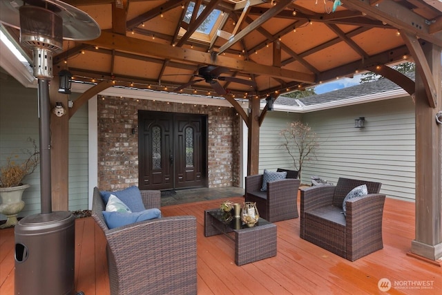 wooden terrace with french doors, outdoor lounge area, ceiling fan, and a gazebo