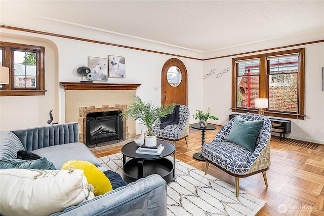 living room with crown molding, a fireplace with flush hearth, baseboards, and a textured ceiling