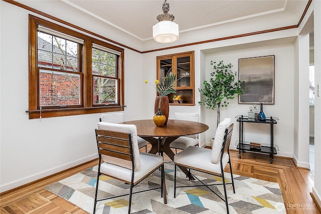 dining space with a textured ceiling, parquet floors, baseboards, and ornamental molding