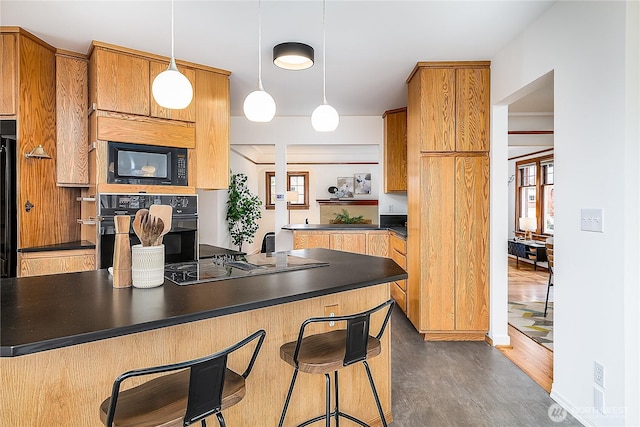 kitchen with dark countertops, pendant lighting, black appliances, and a breakfast bar